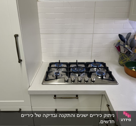 כיריים גז במטבח עם כלים על השיש